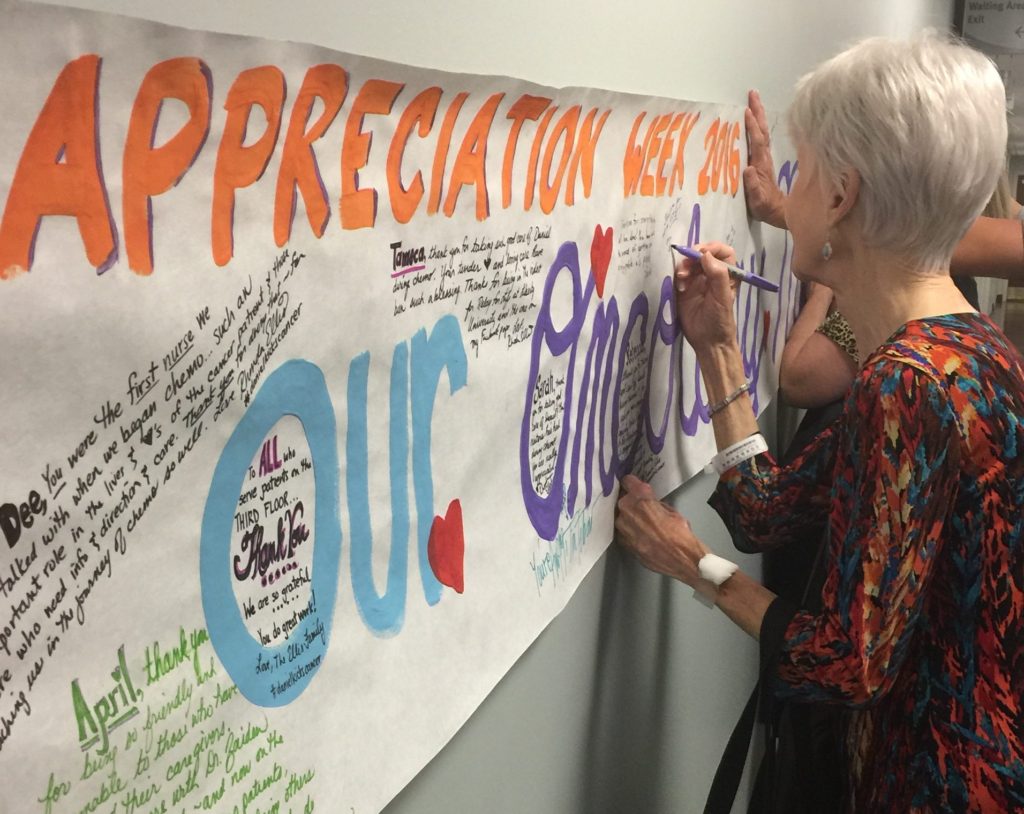 A chemo patient signing the banner for Nurse Appreciation Week